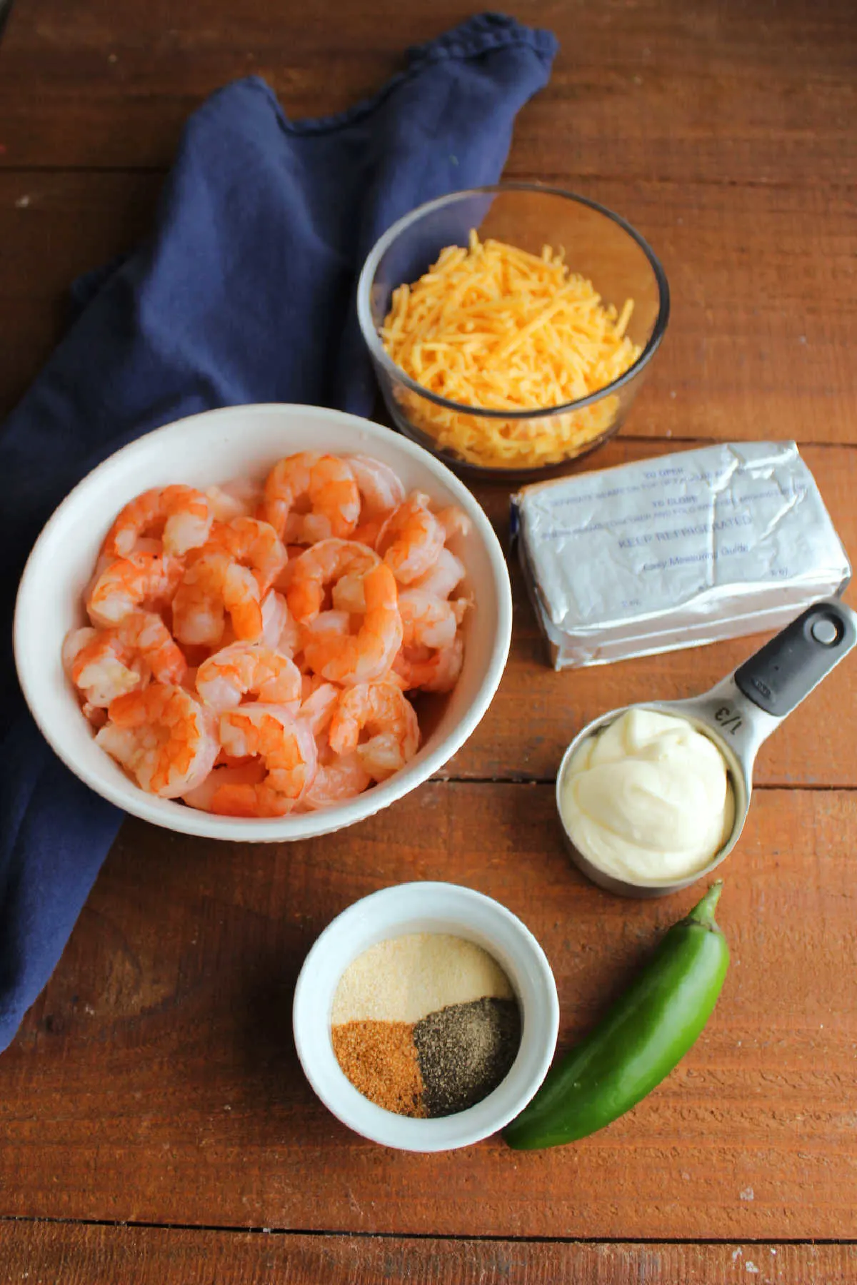 Ingredients for Cajun shrimp dip including shrimp, cream cheese, mayonnaise, jalapeno, spices, and cheddar cheese. 
