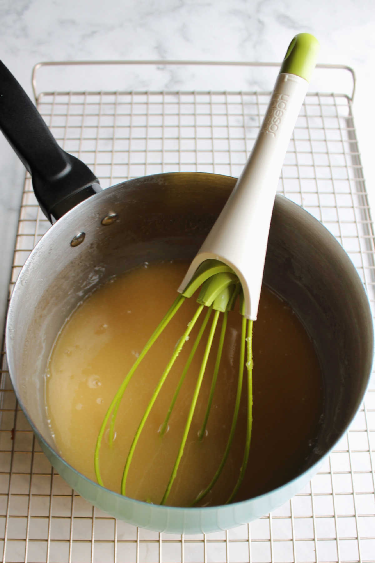 Saucepan of caramelized honey glaze with whisk.