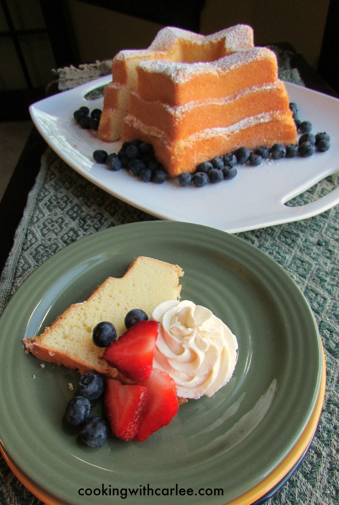 slice of sand torte served with strawberries, blueberries and cream cheese whipped cream.