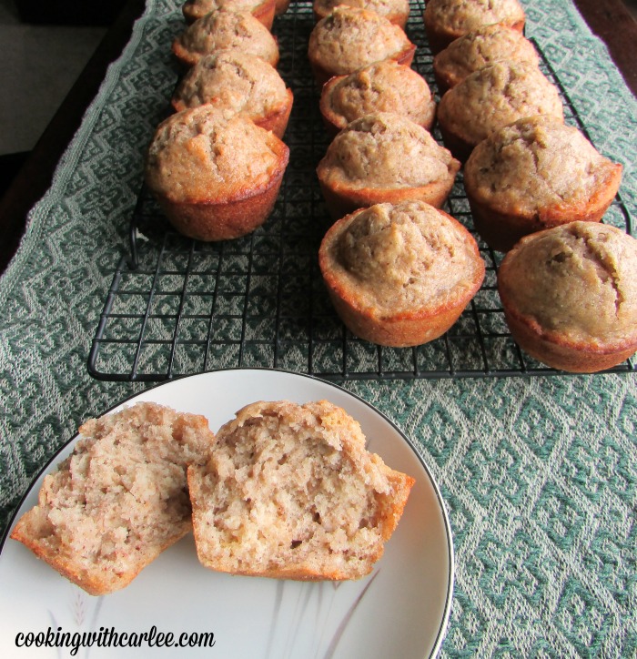 sourdough banana muffin broke in half showing soft center with more muffins on cooling rack in background.