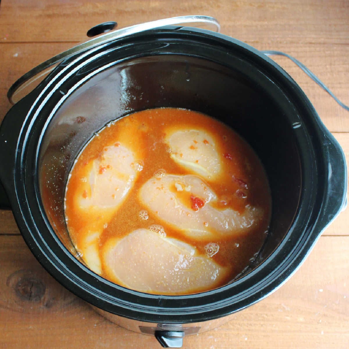 raw chicken breasts in honey based sauce in slow cooker, ready to cook.