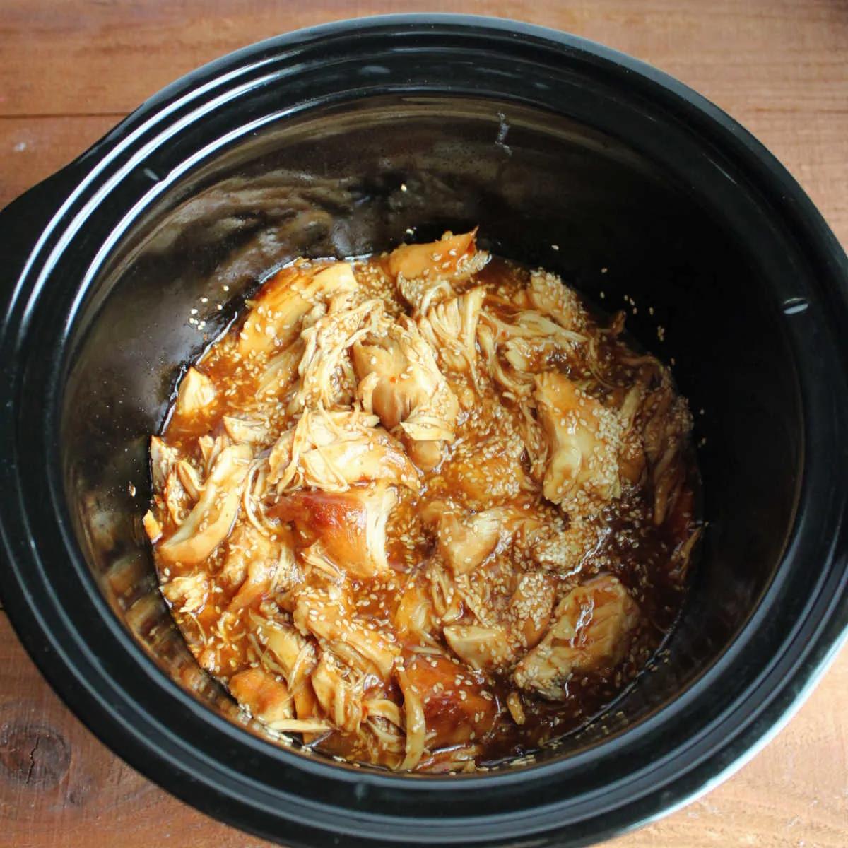 Lightly shredded chunks of chicken in thick sauce in slow cooker.