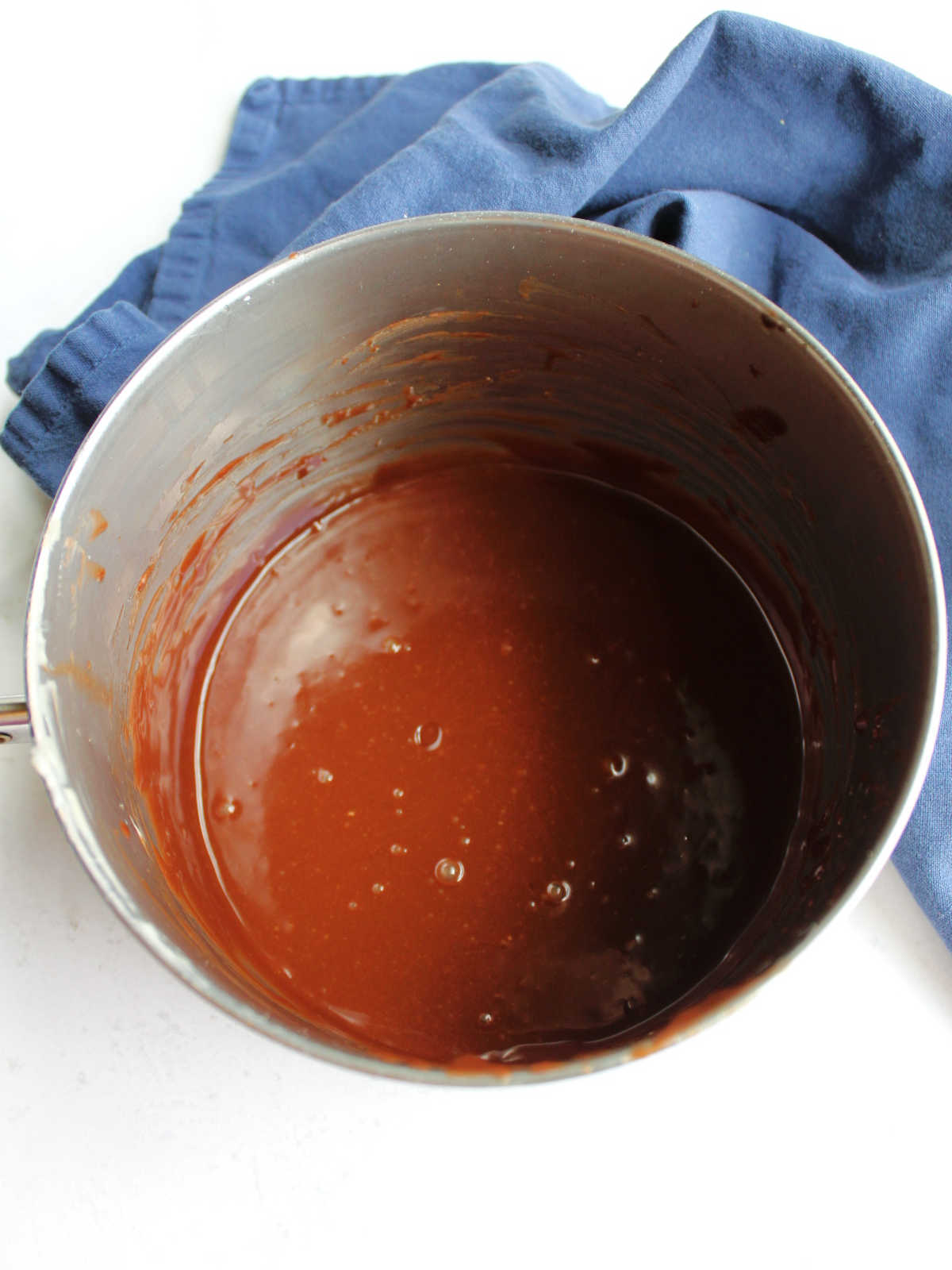 Chocolate icing in saucepan, ready to be poured over cake.
