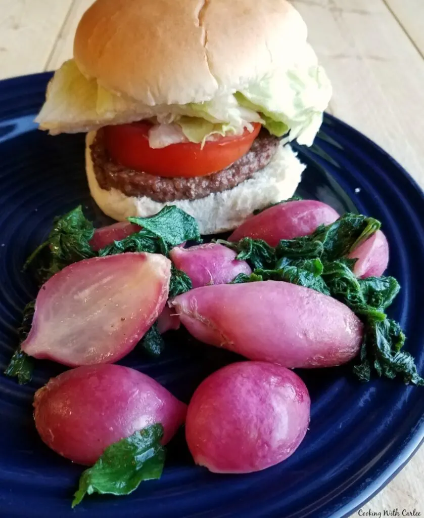 Dinner plate with hamburger and roasted radishes with wilted greens.