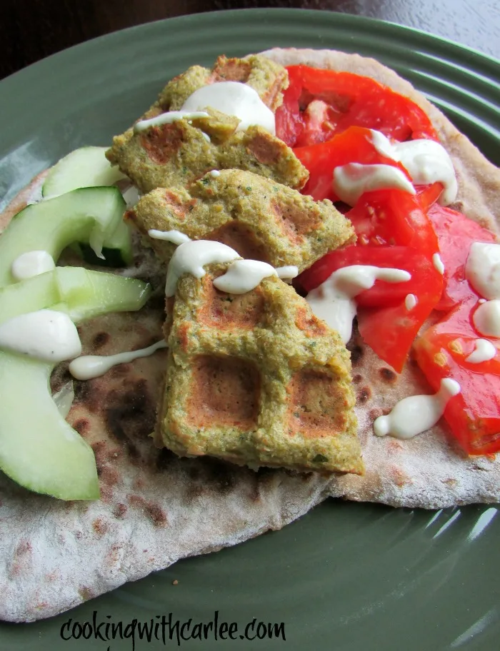 Falafel waffles on pita bread with tomatoes, cucumbers and a drizzle of tahini yogurt sauce.