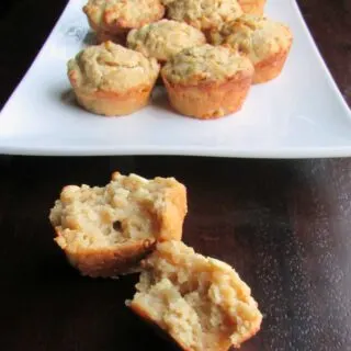 orange sourdough muffins with oatmeal and white chocolate chips on platter with one torn open showing soft center.