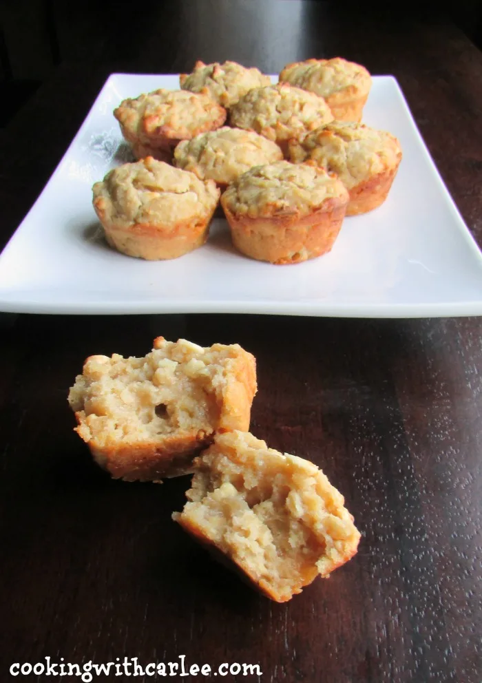 orange sourdough muffins with oatmeal and white chocolate chips on platter with one torn open showing soft center. 