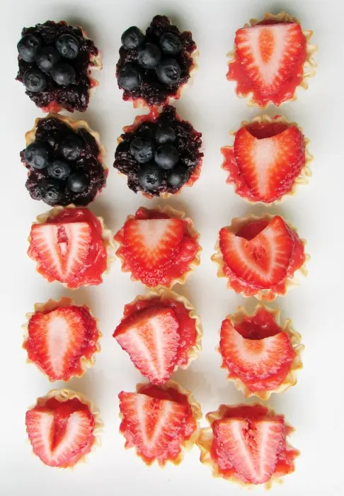 Flag shaped arrangement of strawberry and blueberry tarts, ready to eat.