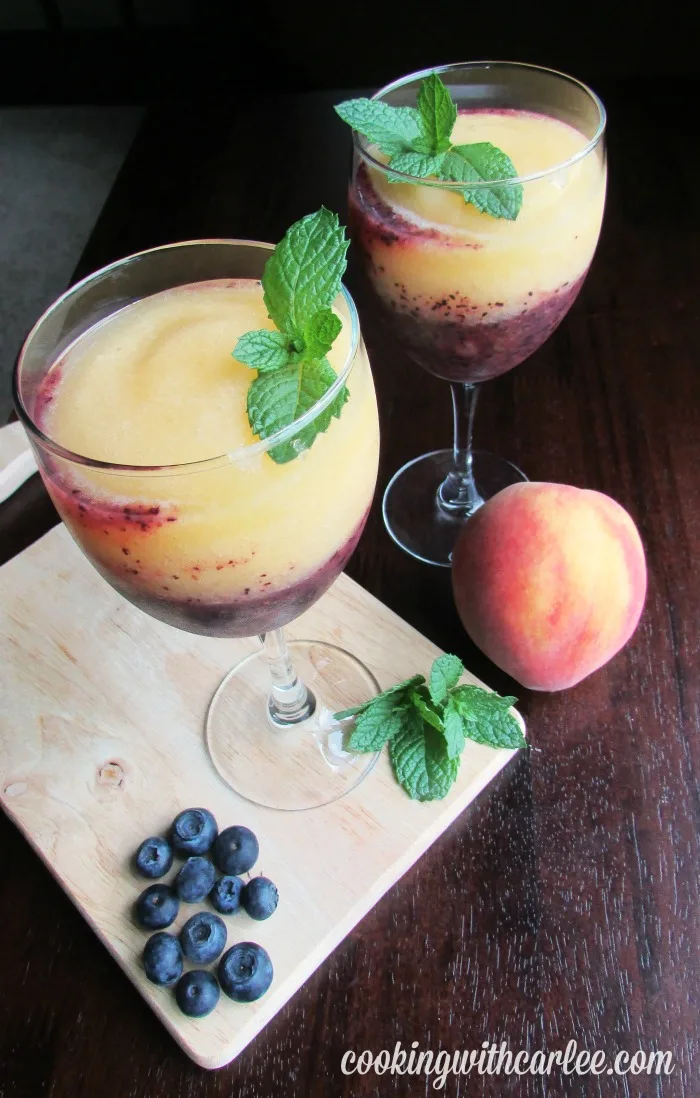 looking down at wine glasses with layers of peach and blueberry wine slush