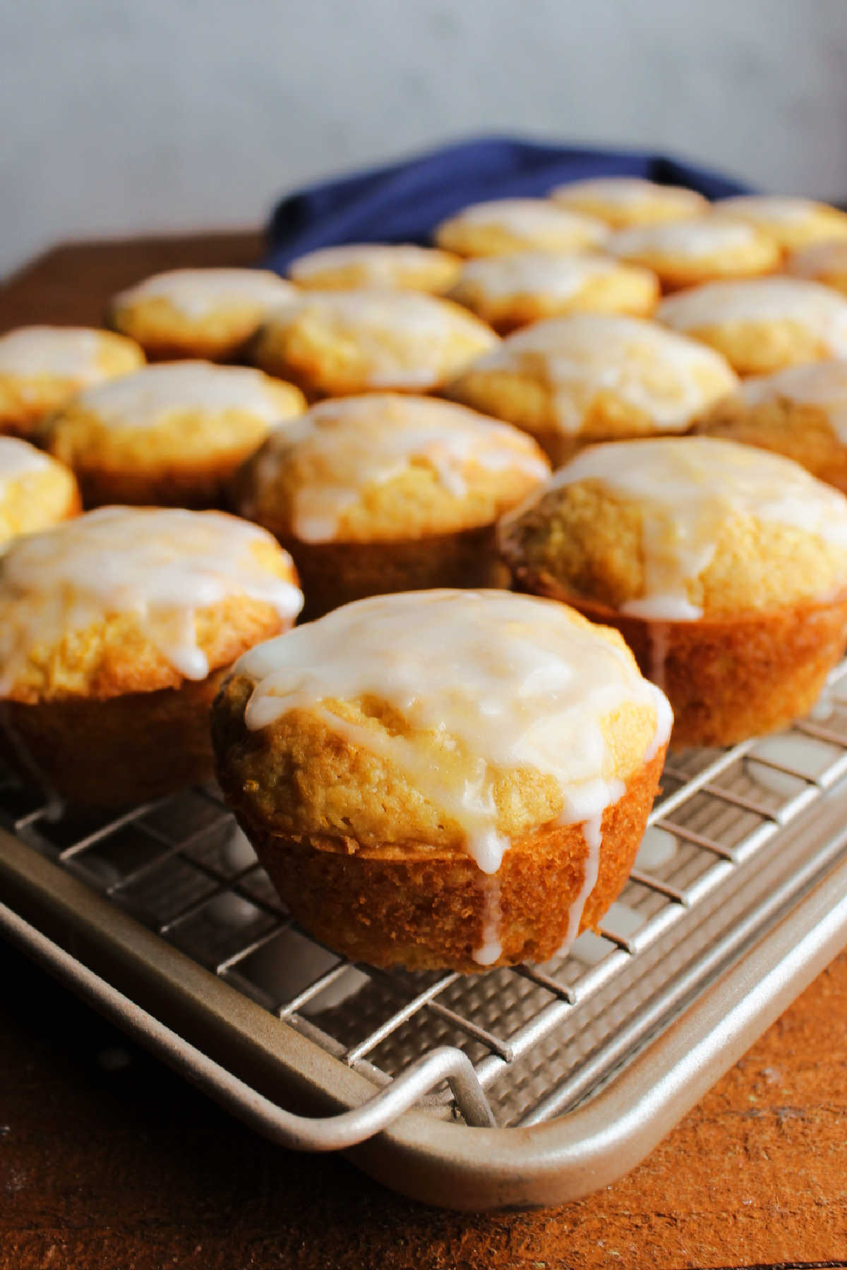 Glazed lemon summer squash muffins on wire rack over baking pan showing the drips going down the muffin onto the pan.