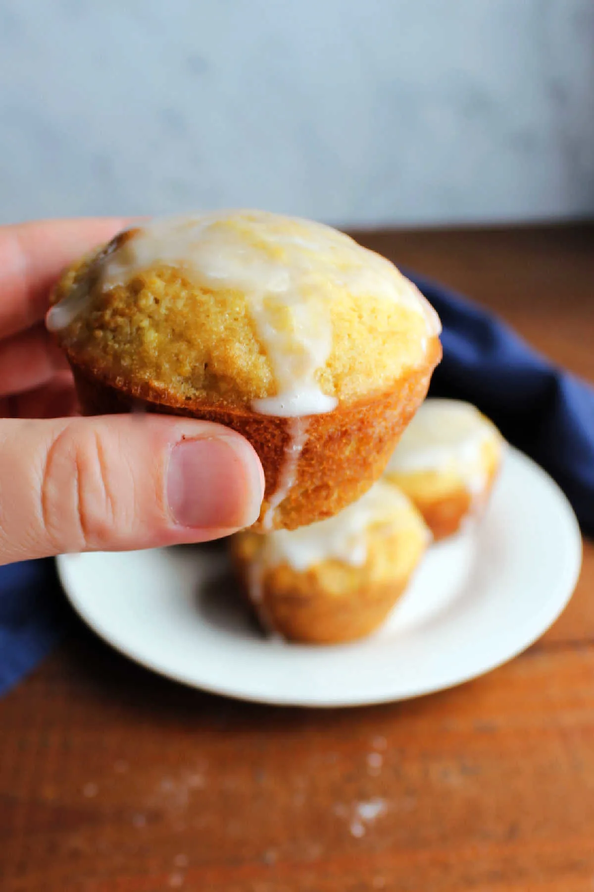 Hand holding a glazed summer squash muffin, ready to eat. 