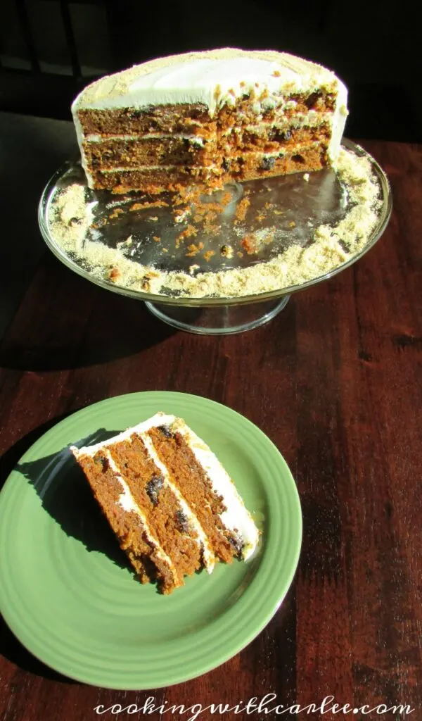Slice of layered carrot cake with raisins on plate, ready to eat. 