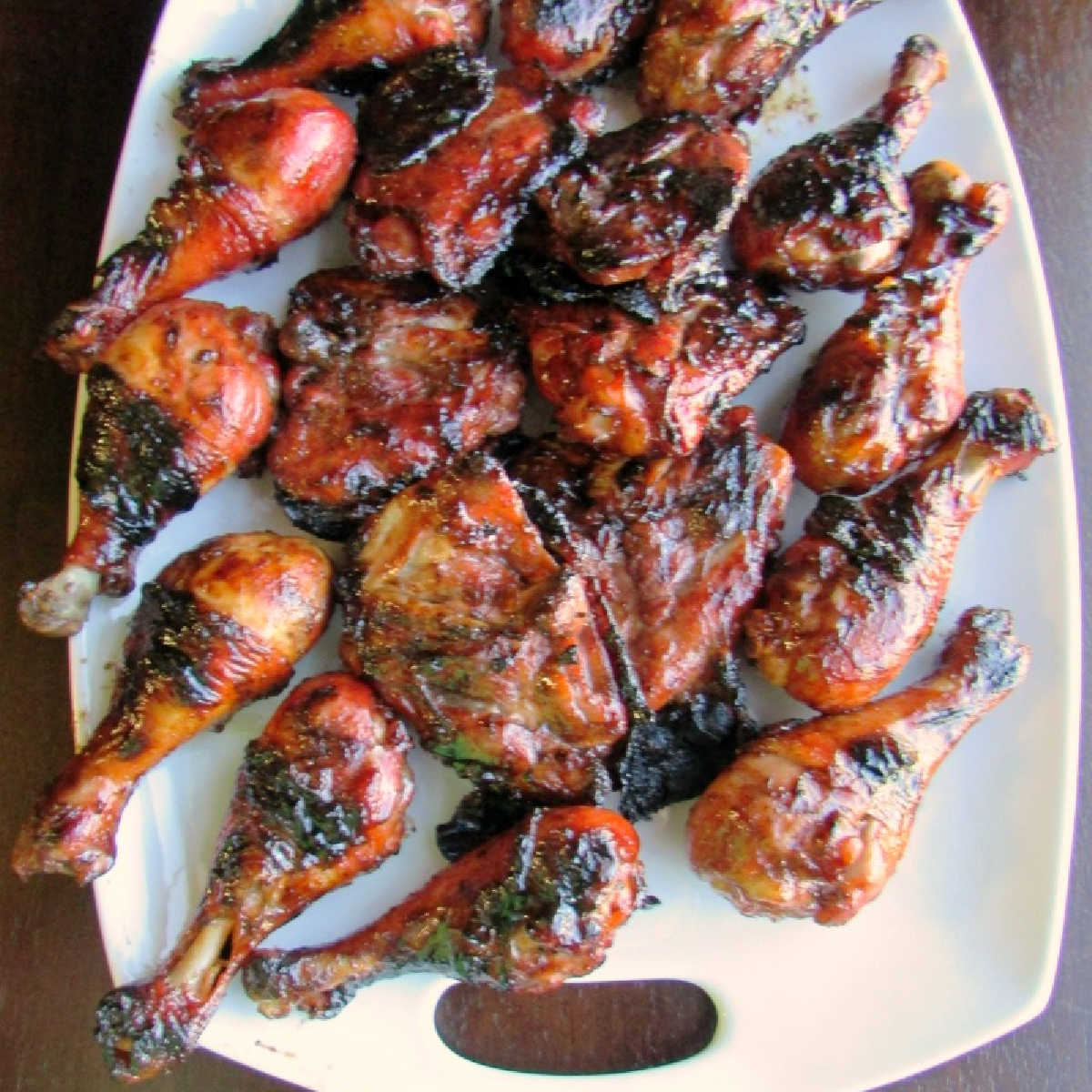 platter of shiny red grilled chicken drumsticks and thighs.
