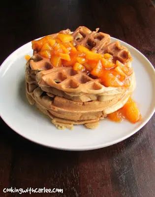 stack of waffles drizzled with cooked peach sauce.