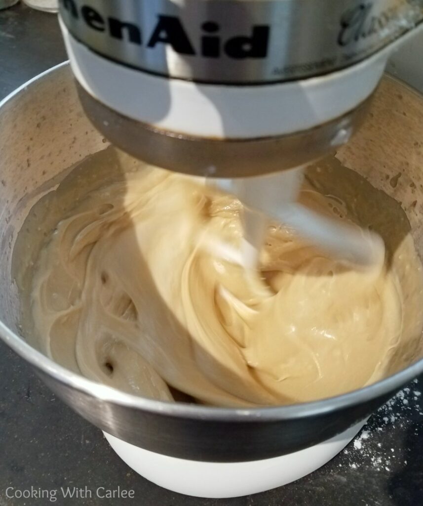 mixer bowl with paddle beating butterscotch frosting.