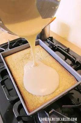 pouring butterscotch frosting over banana cake
