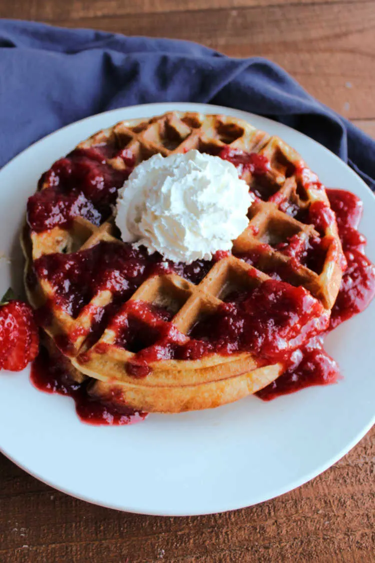 stack of sourdough waffles with strawberries and whipped cream