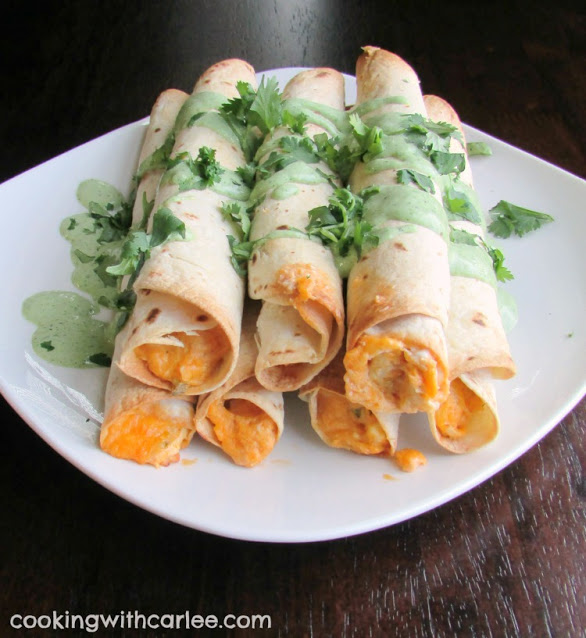pile of taquitos drizzled with cilantro sauce and chopped cilantro.
