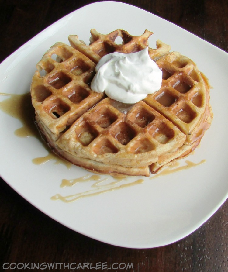 Plate with apple cider waffle topped with caramel and whipped cream, ready to eat. 