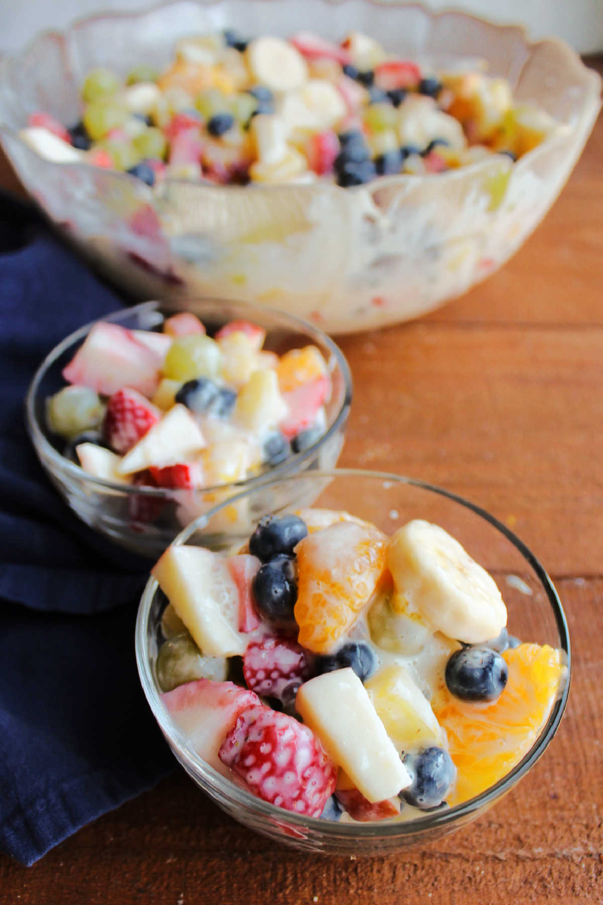 Looking down on small glass bowls filled with creamy fruit salad with condensed milk.