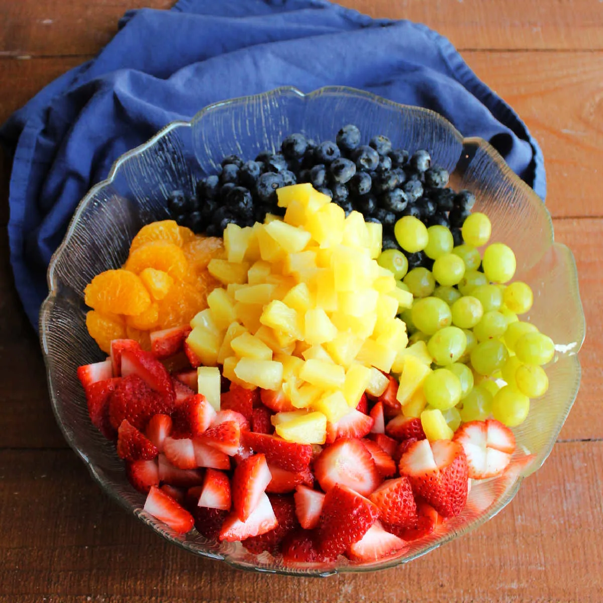 Strawberries, blueberries, grapes, oranges and pineapple added to bowl with apples, banana, and lemon juice.