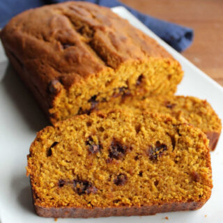 Slices of chocolate chip pumpkin bread with milk chocolate chips on platter.