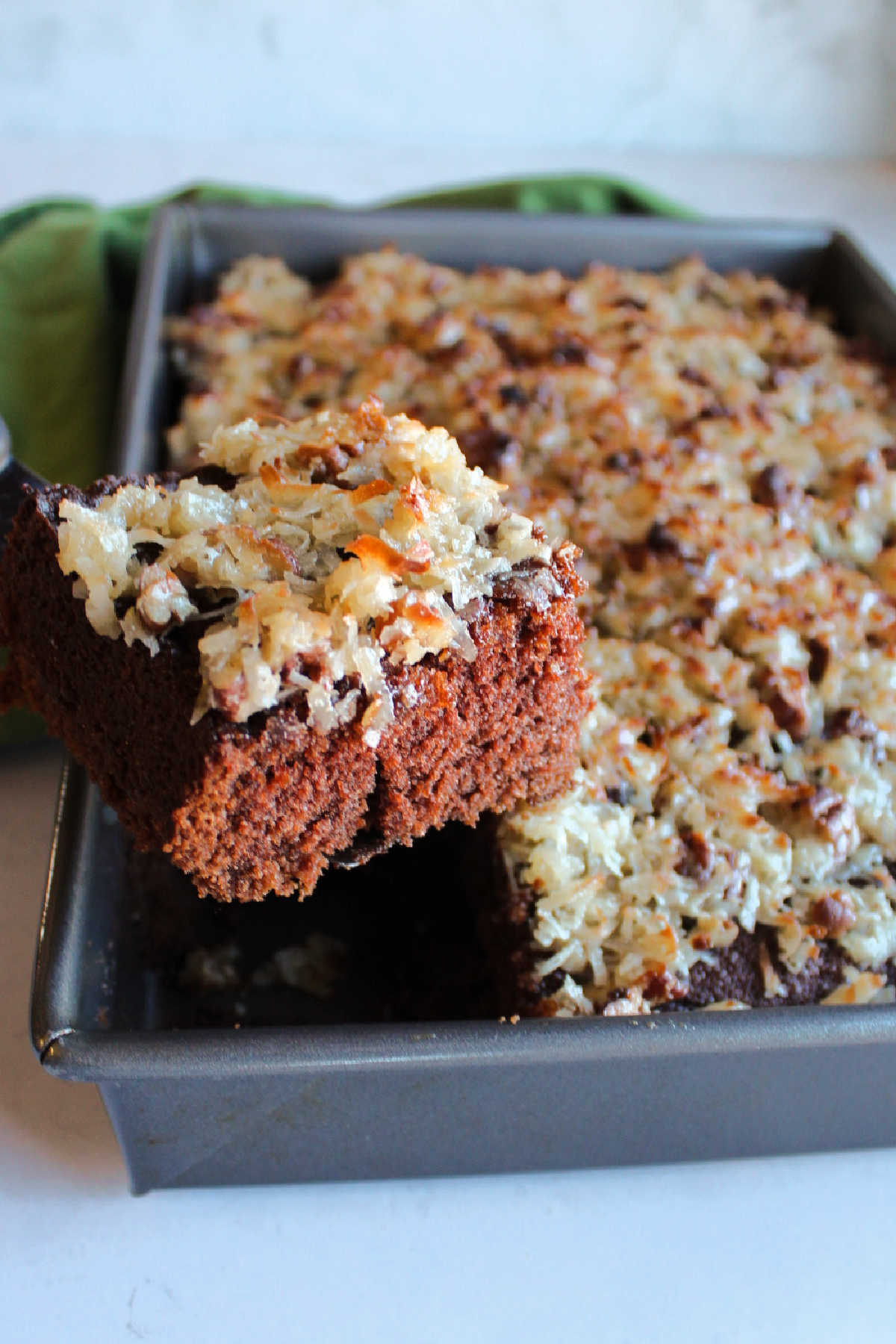 Lifting first piece of German chocolate cake with broiled coconut frosting out of cake pan.