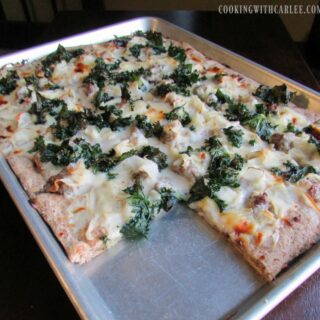 Large sheet pan pizza topped with potatoes, sausage, kale and cheese.