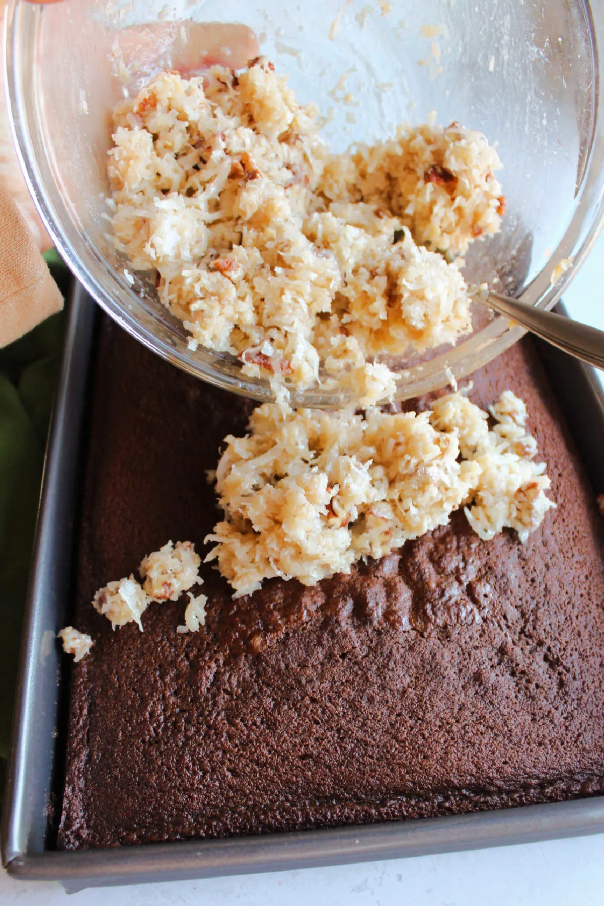 Spreading coconut mixture over cooked German chocolate cake.