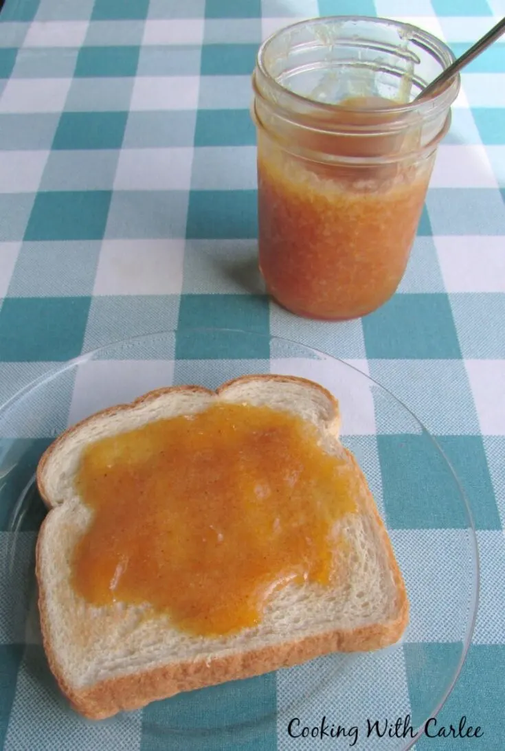 homemade cinnamon peach jam on toast next to jar of jam.