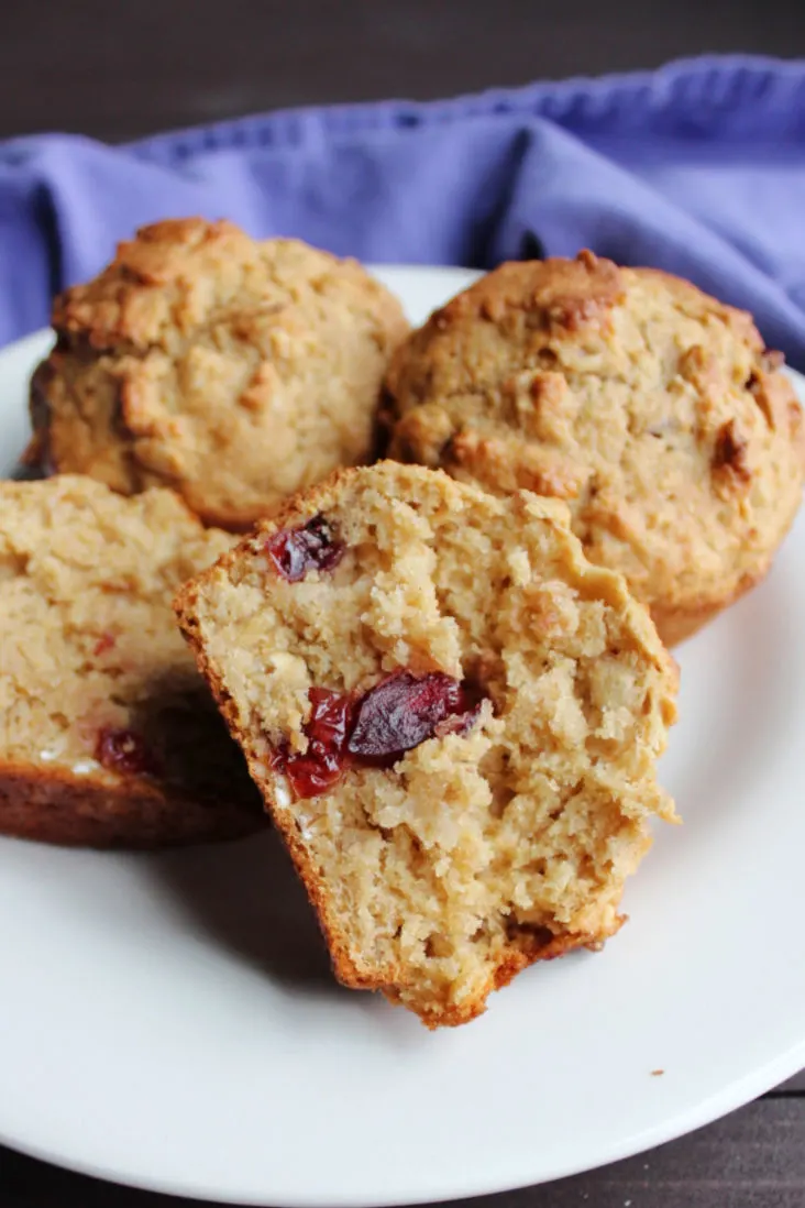plate of muffins showing the soft inside of one with cranberries.