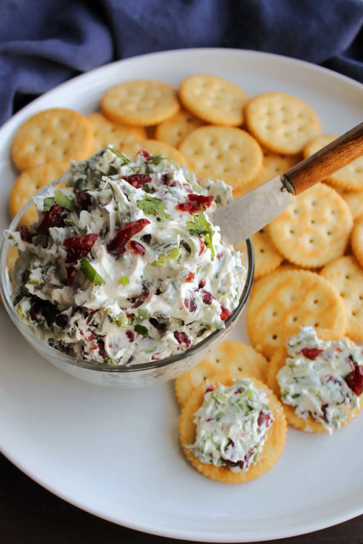 Bowl of jalapeno cranberry cream cheese cracker spread on plate with butter crackers ready to be served. 