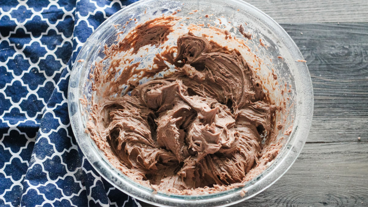 mixing bowl filled with thick chocolate batter made from cake mix for turtle bars