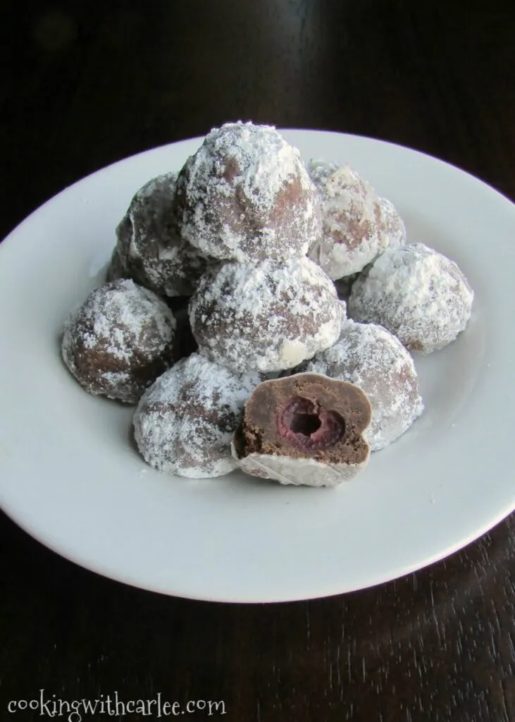 Plate of chocolate covered cherry cookies dusted in powdered sugar.