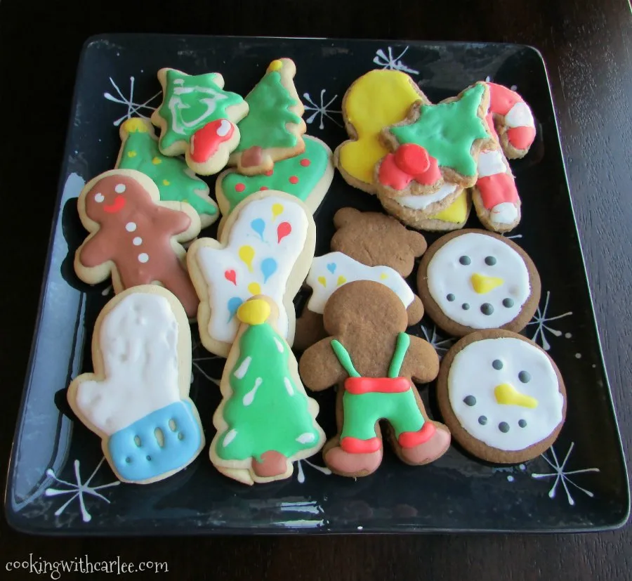Tray of Christmas cookies with sugar cookies, gingerbread men, and toasted oatmeal cookies all decorated with royal icing.