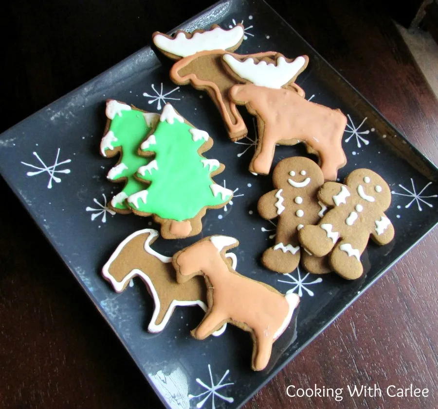 plate of german gingerbread cookies cut into men, moose, trees and goats frosted with royal icing.