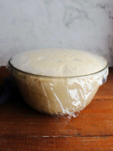 Proofed potato dough in large glass mixing bowl.