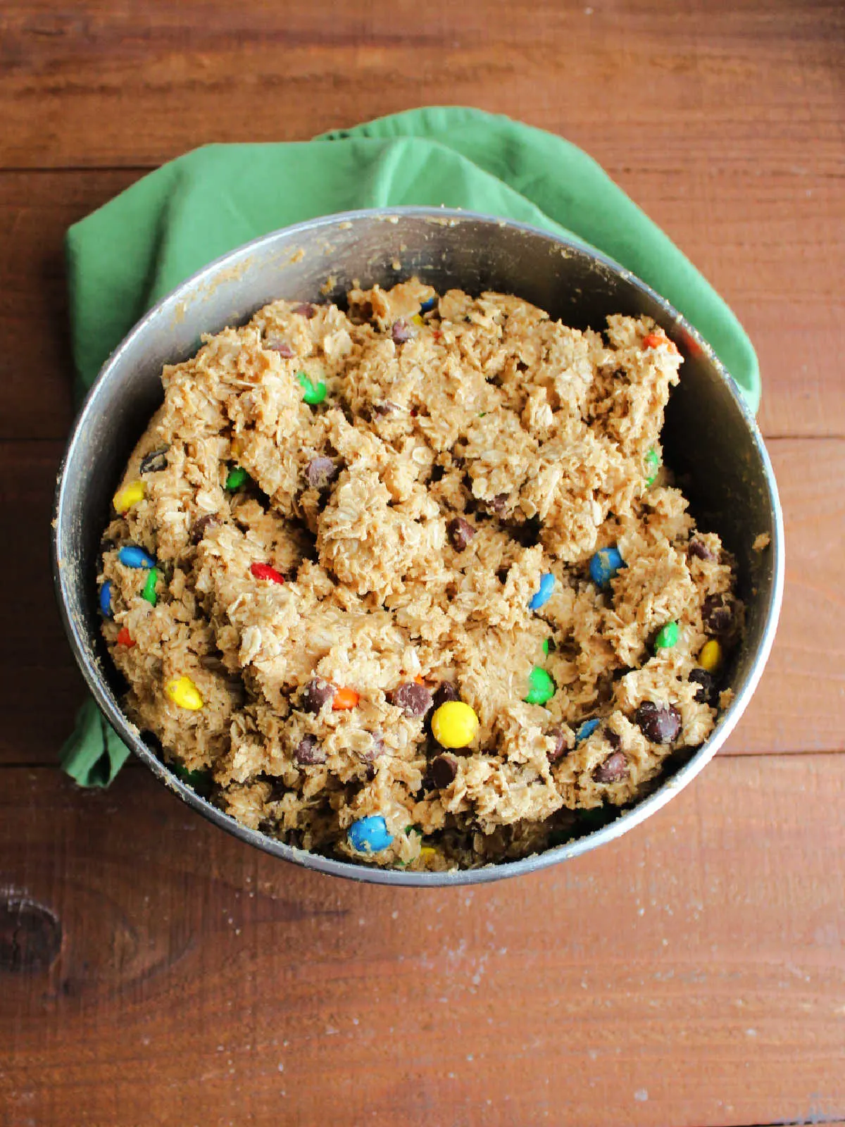 Mixer bowl filled to the brim with monster cookie dough featuring peanut butter, oatmeal, and chocolates.