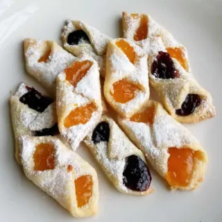 Close up of freshly made apricot and mixed berry kolacky dusted with powdered sugar, ready to eat.
