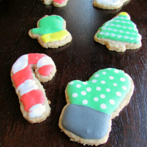 Oatmeal cookies cut into shapes of mittens, candy canes and christmas trees decorated with royal icing.