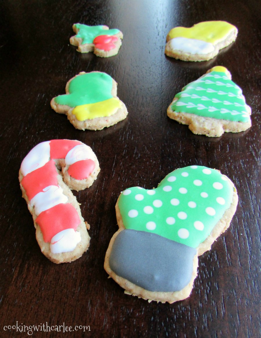 toasted oatmeal cookies cut in mitten, candy cane and Christmas tree shapes with colorful royal icing on top.