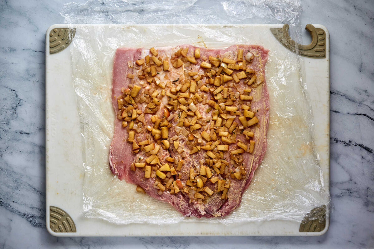 Cooked apple mixture spread over the top of the butterflied pork loin, ready to be rolled up.