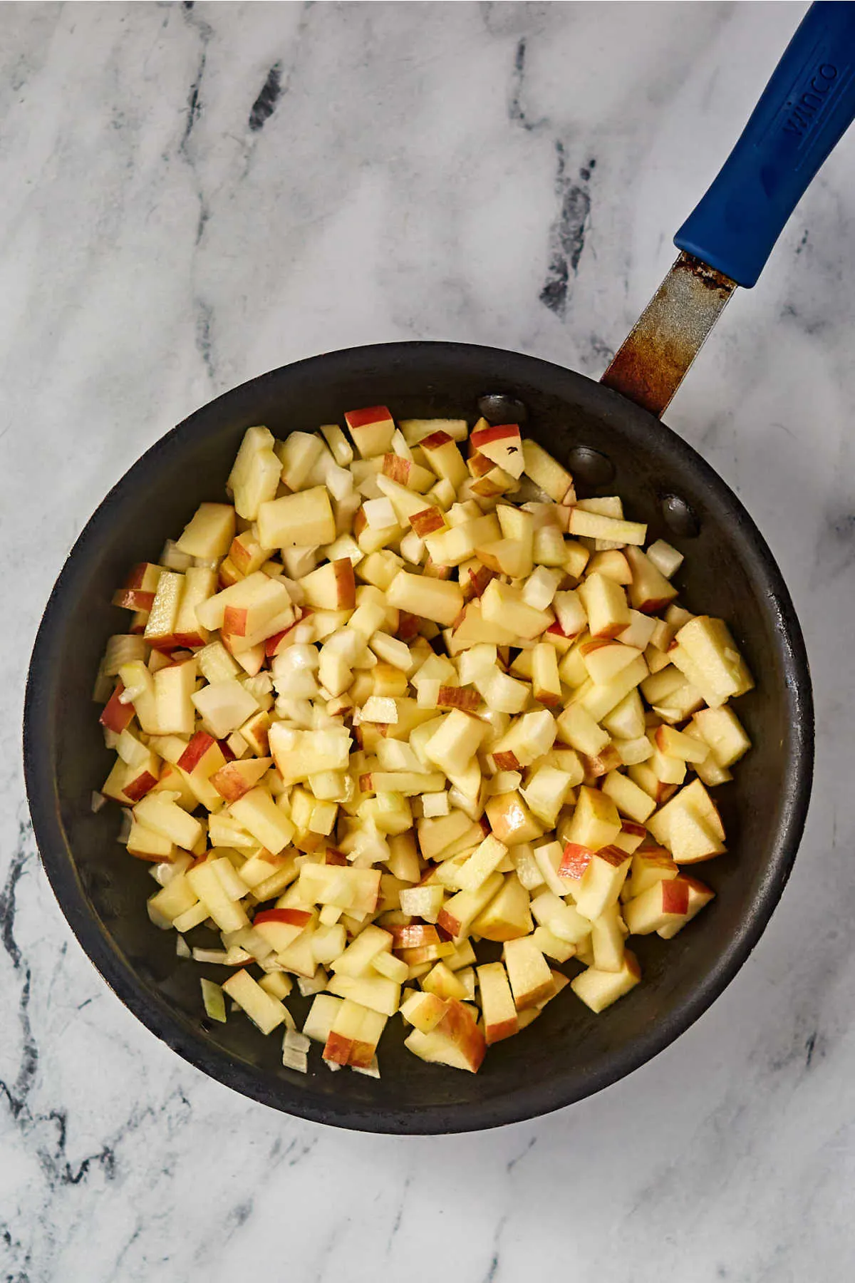 Skillet with chopped onions and apples, ready to be cooked. 