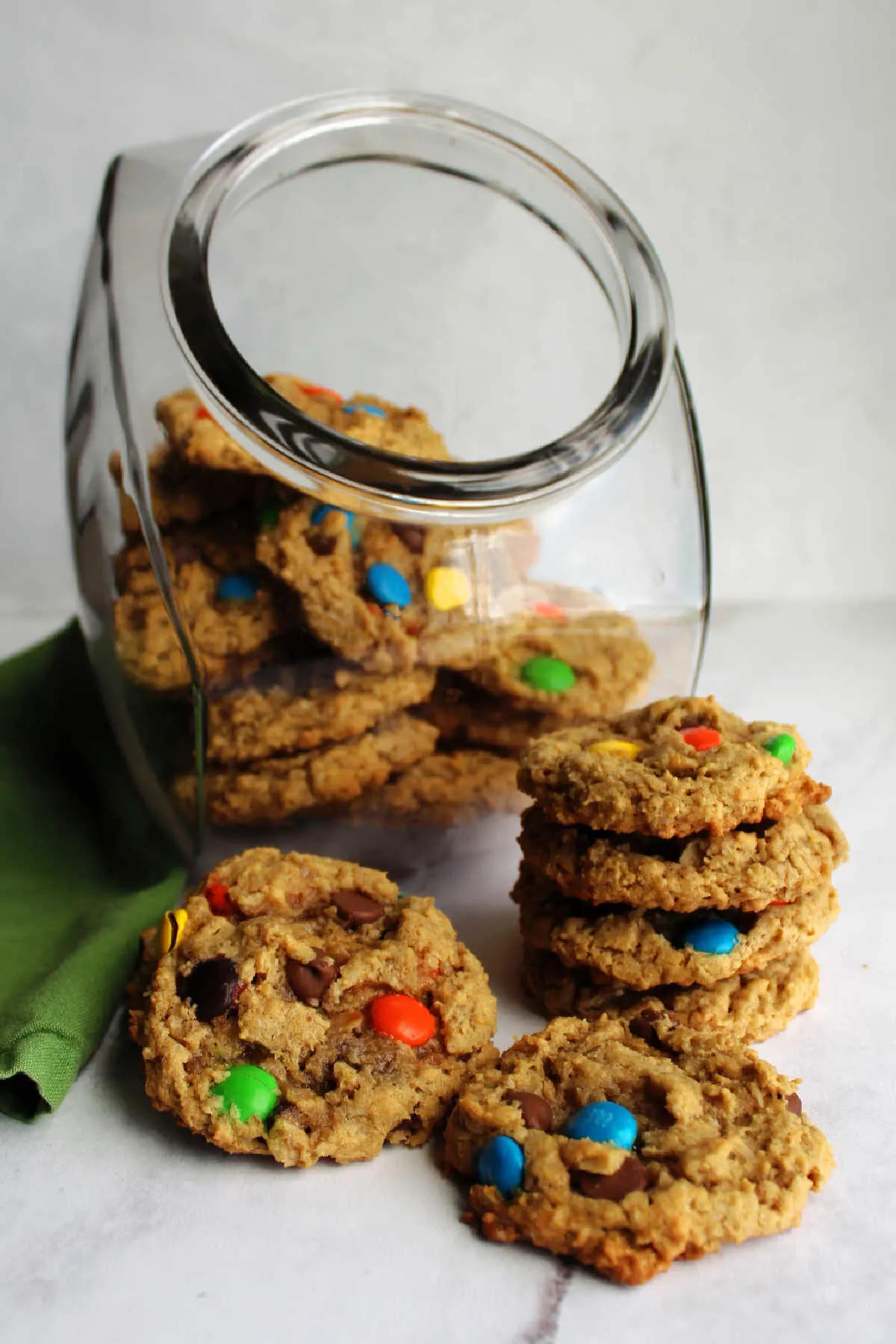 Stack of monster cookies in front of cookie jar filled with more.