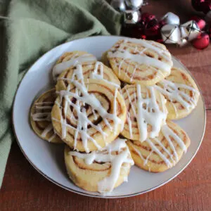 Plate of cinnamon roll cookies topped with cream cheese icing.
