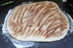 Soft potato dough rolled out into a square shape topped with melted butter and cinnamon sugar.