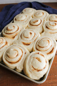 Proofed cinnamon rolls, now twice their size and filling the pan, ready to go in the oven.