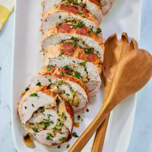 Slices of pork loin rolled around an apple and rosemary filling on serving platter.