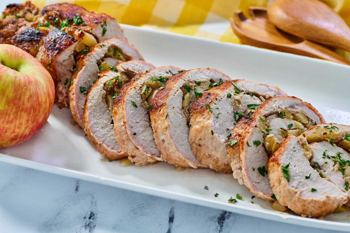 Sliced apple stuffed pork loin showing pork wrapped around a cooked apple filling, ready to be served. 