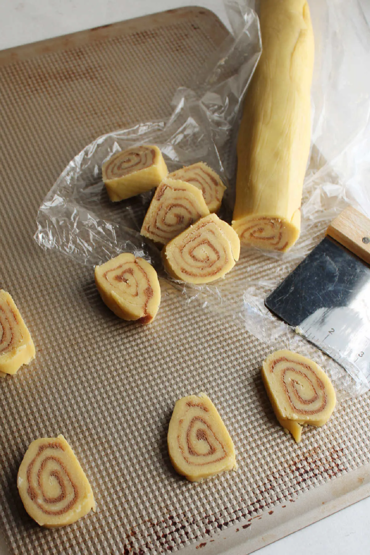 Slicing chilled log of cinnamon cookie dough and putting cookies on tray to bake.